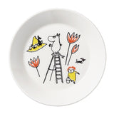 Kuvassa Muumi -lautanen, missä on Tove Janssonin Punaiselle Ristille piirtämä Muumipeikko-hahmo kiipeilee tikapuilla.